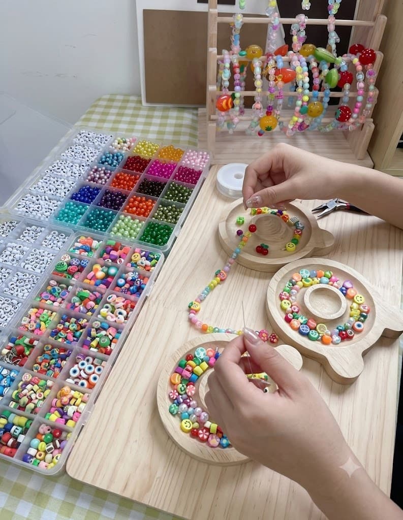 Hands threading colourful beads at a bracelet-making welcome station